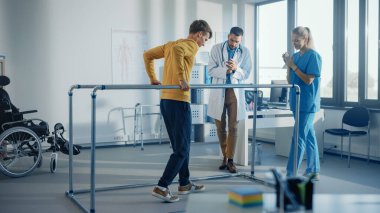Hastane Fizik Terapisi: Yaralı Güçlü Hasta İlk Adımlarını Yapıyor, Paralel Barlar İçin Yürüyor. Fizyoterapist, Rehabilitasyon Doktoru Yardım Engelli Kişi.