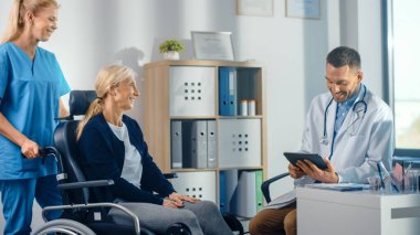 Hastane Fizyoterapisi: Tekerlekli sandalyedeki güçlü kıdemli kadın, Dost Rehabilitasyon Fizyoterapisti Doktorlarla Görüştü, Engelli Hastalara Rehabilitasyon Tedavisi Verdi