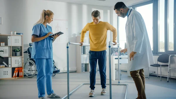 Hastane Fizik Terapisi: Yaralı Erkek Hasta Paralel Çubuklarda Yürüyor. Fizyoterapist, Rehabilitasyon Doktoru, Yardım, Yardım, Engelli Kişi.