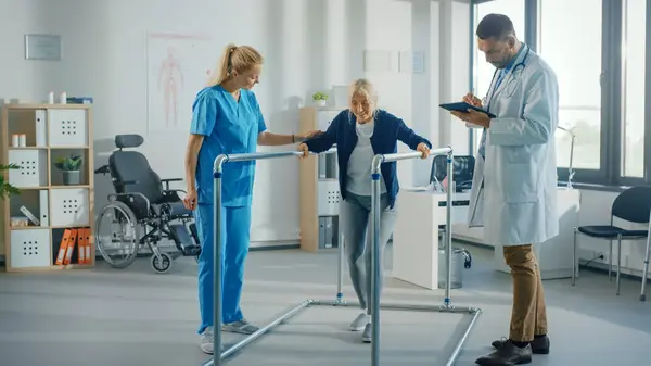 Hastane Fizik Terapisi: Yaralı Yaşlı Kadın Hastaların Paralel Paralel Çubuklarda Başarılı Yürüyüşleri Portresi. Fizyoterapist, Rehabilitasyon Doktoru, Yardım, Engelli Hastaya Yardım