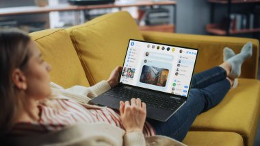 Güzel Beyaz Dişi Ev Oturma Odasında Arkadaşlarıyla Sohbet Etmek İçin Bir Koltukta Uzanırken Dizüstü Bilgisayar Kullanıyor. Sosyal Medya Pazarlamacısı Evden Çalışıyor, İnternette Sörf yapıyor.