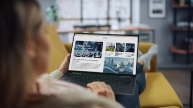 Güzel Beyaz Kadın, Kanepe üzerinde yatarken Ev Oturma Odasında Son Haberleri Okumak İçin Dizüstü bilgisayar kullanıyor. Evden Çalışan Serbest Uzman İnternet Sörfü.