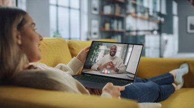 Genç Bayan Ev Oturma Odası dizüstü bilgisayarında Yakışıklı Afrikalı Erkek Arkadaşıyla Görüntülü Konuşuyor. Ev Uzmanı 'ndan internet üzerinden müdürle telefon görüşmesi yapıyorum..