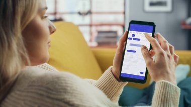 Güzel Otantik Kadın Kanepe üzerinde yatarken Evde Oturma Odasında Takvim Uygulaması ile Akıllı Telefon Kullanıyor. Planlar yapıyor ve bir günlük etkinlik programını kontrol ediyor..