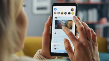 Bir Kadın Akıllı Telefonun Yakın Çekimi ve Sosyal Ağ Kontrol, Haberleri İzleme. Oturma odasındaki koltukta uzanıyor..