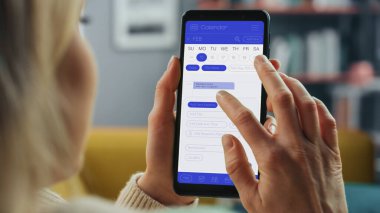 Güzel Otantik Kadın Kanepe üzerinde yatarken Evde Oturma Odasında Takvim Uygulaması ile Akıllı Telefon Kullanıyor. Planlar yapıyor ve bir günlük etkinlik programını kontrol ediyor..