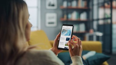 Güzel Otantik Kadın Teknoloji Hakkında Son Haberleri ve Makaleleri Okumak İçin Akıllı Telefon Kullanıyor. Ev Oturma Odası 'nda bir koltukta yatıyor. Evden Çalışan Serbest Çalışan, İnternette Sörf Yapan.