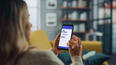 Güzel Otantik Kadın Kanepe üzerinde yatarken Evde Oturma Odasında Takvim Uygulaması ile Akıllı Telefon Kullanıyor. Planlar yapıyor ve bir günlük etkinlik programını kontrol ediyor..