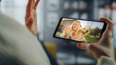 Ev Oturma Odası 'ndan Smartphone' da Güzel Arkadaşı ile Bir Köpekle Oynayan Bir Kadın Sohbetinin Kapanışı. Serbest Çalışan İnternetten Bir Müşteriyle Sohbet Ediyor.