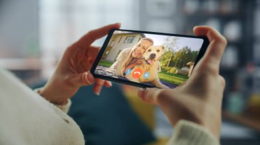 Ev Oturma Odası 'ndan Smartphone' da Güzel Arkadaşı ile Bir Köpekle Oynayan Bir Kadın Sohbetinin Kapanışı. Serbest Çalışan İnternetten Bir Müşteriyle Sohbet Ediyor.