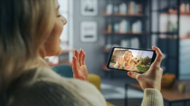 Ev Oturma Odası 'ndan Smartphone' da Güzel Arkadaşı ile Bir Köpekle Oynayan Bir Kadın Sohbetinin Kapanışı. Serbest Çalışan İnternetten Bir Müşteriyle Sohbet Ediyor.
