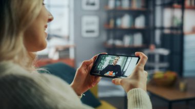 Oturma odasından Smartphone 'daki Yakışıklı Beyaz Arkadaşı ile Kadın Sohbetinin Kapanışı. Freelancer internet üzerinden müdürle evden arama yapıyor..