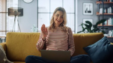 Güzel kadın uzman, bir kanepede otururken dizüstü bilgisayarında video görüşmesi yapıyor. Evden Çalışan ve İnternet üzerinden İş Arkadaşları ve Müşterilerle Konuşan Serbest Çalışan.