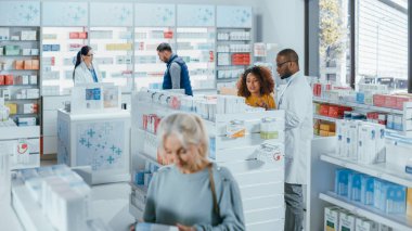 Eczane: Çeşitli Etnik Müşteri Grubu Rafları Tarayarak, İlaç, İlaç, Vitamin, Ek Malzemeler, Kasiyerdeki Profesyonel Eczacı 'dan SağIık Bakımı Ürünleri