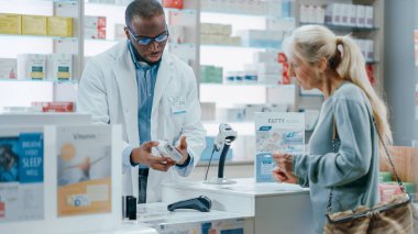 Eczane Kontrol Tezgahı: Siyah Erkek Eczacı Reçeteli İlaç Kullanımı ve Kullanım Kılavuzunu Açıklıyor Güzel, Kıdemli Kadın Müşteri Bağlantısız Kredi Kartıyla Terminal 'e Ödeme Yapıyor