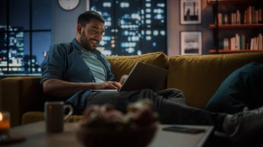 Evdeki Evdeki Gece ve Tablet Bilgisayarı 'nda, Rahat Karanlık Oturma Odasında, Koltukta Oturan Güzel Otantik Latin Kadın. İnterneti geziyor, Stylus Kalem 'le yazı ve çizim yapıyor..