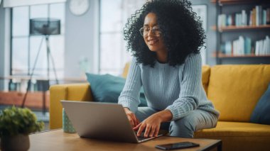 Evdeki Evdeki Gece ve Tablet Bilgisayarı 'nda, Rahat Karanlık Oturma Odasında, Koltukta Oturan Güzel Otantik Latin Kadın. İnterneti geziyor, Stylus Kalem 'le yazı ve çizim yapıyor..