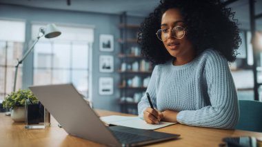 Evdeki Evdeki Gece ve Tablet Bilgisayarı 'nda, Rahat Karanlık Oturma Odasında, Koltukta Oturan Güzel Otantik Latin Kadın. İnterneti geziyor, Stylus Kalem 'le yazı ve çizim yapıyor..