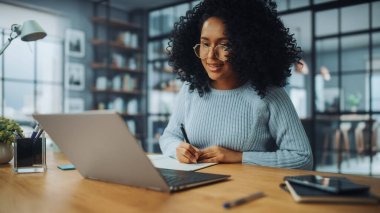 Evdeki Evdeki Gece ve Tablet Bilgisayarı 'nda, Rahat Karanlık Oturma Odasında, Koltukta Oturan Güzel Otantik Latin Kadın. İnterneti geziyor, Stylus Kalem 'le yazı ve çizim yapıyor..