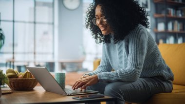 Evdeki Evdeki Gece ve Tablet Bilgisayarı 'nda, Rahat Karanlık Oturma Odasında, Koltukta Oturan Güzel Otantik Latin Kadın. İnterneti geziyor, Stylus Kalem 'le yazı ve çizim yapıyor..