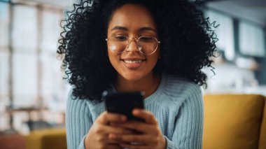 Evdeki Evdeki Gece ve Tablet Bilgisayarı 'nda, Rahat Karanlık Oturma Odasında, Koltukta Oturan Güzel Otantik Latin Kadın. İnterneti geziyor, Stylus Kalem 'le yazı ve çizim yapıyor..