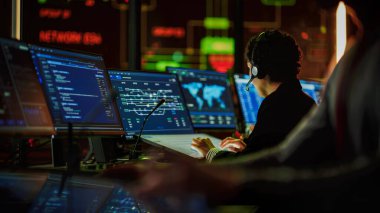 Profesyonel IT Teknik Destek Uzmanı ve Yazılım Geliştiricisi Dijital Ekranlarla Bilgisayar Kontrol Odasında çalışıyor. Çalışan Mikrofonlu Kulaklık Kullan ve Konuşurken Çağrı Yap.