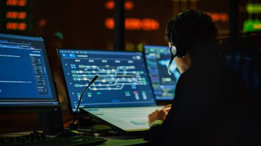 Profesyonel IT Teknik Destek Uzmanı ve Yazılım Geliştiricisi Dijital Ekranlarla Bilgisayar Kontrol Odasında çalışıyor. Çalışan Mikrofonlu Kulaklık Kullan ve Konuşurken Çağrı Yap.