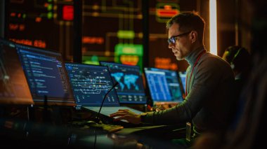 Profesyonel IT Teknik Destek Uzmanı ve Yazılım Geliştiricisi Dijital Ekranlarla Bilgisayar Kontrol Odasında çalışıyor. Çalışan Mikrofonlu Kulaklık Kullan ve Konuşurken Çağrı Yap.