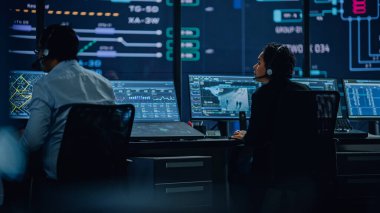 Profesyonel IT Teknik Destek Uzmanı ve Yazılım Geliştiricisi Dijital Ekranlarla Bilgisayar Kontrol Odasında çalışıyor. Çalışan Mikrofonlu Kulaklık Kullan ve Konuşurken Çağrı Yap.