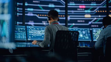 Profesyonel IT Teknik Destek Uzmanı ve Yazılım Geliştiricisi Dijital Ekranlarla Bilgisayar Kontrol Odasında çalışıyor. Çalışan Mikrofonlu Kulaklık Kullan ve Konuşurken Çağrı Yap.