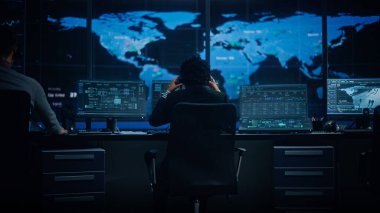 Profesyonel IT Teknik Destek Uzmanı ve Yazılım Geliştiricisi Dijital Ekranlarla Bilgisayar Kontrol Odasında çalışıyor. Çalışan Mikrofonlu Kulaklık Kullan ve Konuşurken Çağrı Yap.