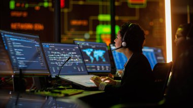 Profesyonel IT Teknik Destek Uzmanı ve Yazılım Geliştiricisi Dijital Ekranlarla Bilgisayar Kontrol Odasında çalışıyor. Çalışan Mikrofonlu Kulaklık Kullan ve Konuşurken Çağrı Yap.