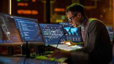 Profesyonel IT Teknik Destek Uzmanı ve Yazılım Geliştiricisi Dijital Ekranlarla Bilgisayar Kontrol Odasında çalışıyor. Çalışan Mikrofonlu Kulaklık Kullan ve Konuşurken Çağrı Yap.