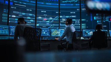 Profesyonel IT Teknik Destek Uzmanı ve Yazılım Geliştiricisi Dijital Ekranlarla Bilgisayar Kontrol Odasında çalışıyor. Çalışan Mikrofonlu Kulaklık Kullan ve Konuşurken Çağrı Yap.