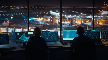 Çeşitli Hava Trafik Kontrol Ekibi gece modern bir havaalanı kulesinde çalışıyor. Ofis Odası, Kontrol Edenler için Uçak Uçuş Radar Verisi, Navigasyon Ekranlarıyla Masaüstü Bilgisayarı ile Doludur.
