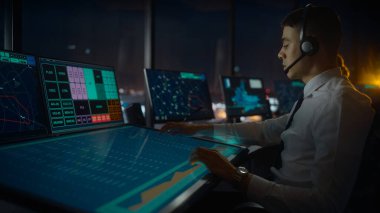 Havalimanı Kulesi 'nde Kulaklık Konuşması yapan Erkek Hava Trafik Kontrolörü. Ofis Odası, Takım için Navigasyon Ekranları, Uçak Gidiş ve Gelen Veri ile Masaüstü Bilgisayarı ile Doludur.