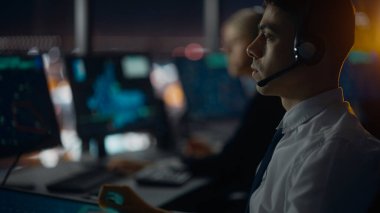 Havalimanı Kulesi 'nde Kulaklık Konuşması yapan Erkek Hava Trafik Kontrolörü. Ofis Odası, Takım için Navigasyon Ekranları, Uçak Gidiş ve Gelen Veri ile Masaüstü Bilgisayarı ile Doludur.