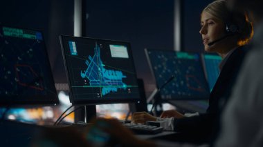Gece Havalimanı Kulesi 'nde Kulaklıklı Kadın Hava Trafik Kontrolörü. Ofis odası, Takım için Uçak Uçuş Radar Verisi, Navigasyon Ekranları ve Masaüstü Bilgisayarlarıyla dolu.