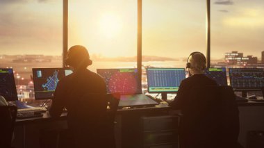 Günbatımında Modern Havaalanı Kulesi 'nde çalışan çeşitli Hava Trafik Kontrol Ekibi. Ofis Odası Masaüstü Bilgisayarı ile dolu Navigasyon Ekranları, Uçak Gidiş ve Denetleyiciler için Gelen Veri.