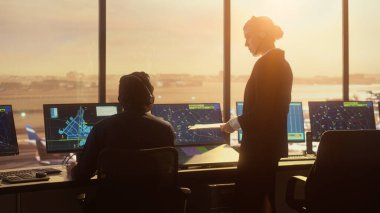 Günbatımında Modern Havaalanı Kulesi 'nde çalışan çeşitli Hava Trafik Kontrol Ekibi. Kontrolörler, Bilgisayarlarla dolu bir odada alkışlayan ellerle yeni bir ticari uçağın kalkışını kutluyorlar..