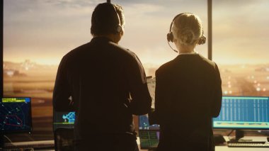 Havalimanı Kulesi 'nde Kulaklıklı Kadın ve Erkek Hava Trafik Kontrolörleri. Ofis Odası Masaüstü Bilgisayarı ile dolu Navigasyon Ekranları, Kontrol Edenler için Uçak Uçuş Radar Verisi.