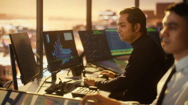 Havalimanı Kulesi 'ndeki Erkek Hava Trafik Kontrolörü ve Kulaklık Konuşması. Ofis Masaüstü Bilgisayarı ile dolu Navigasyon Ekranları, Uçak Uçuş Radar Verisi.