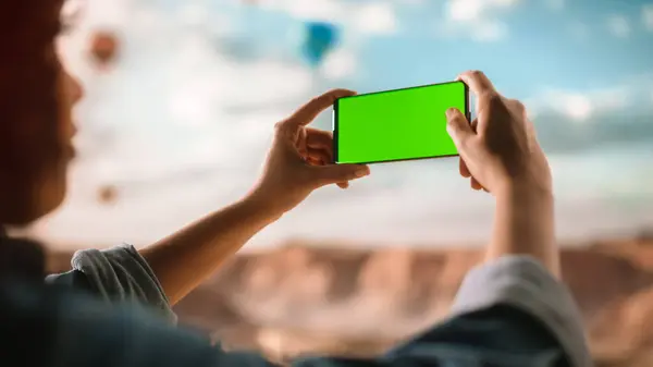 多族游民的特写卷发风格在洛基峡谷的绿色屏幕显示手机上拍了一张智能手机照片 高山国家公园热气球节 — 图库照片
