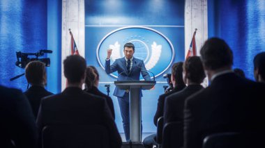 Hükümet Binası 'ndaki basın konferansında konuşan genç temsilci. Basın sözcüsü zirvede konuşma yapacak. Bakan Kongreye Konuşuyor. Büyük Britanya Bayraklarıyla Arkaplan.