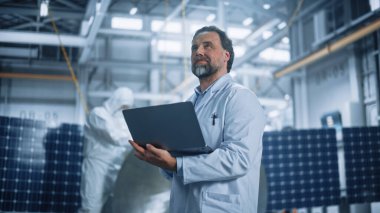 Erkek Mühendis, uydu inşaatında çalışırken dizüstü bilgisayar kullanıyor. Uzay Ajansı Üretim Tesisi: Bilim adamları Uzay Keşfi, Gözlem Görevi İçin Uzay Aracı Geliştirdi, Birleştirdi