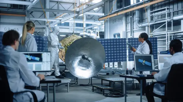 Technicians in Protective Suits Working on Satellite Construction, under Chief Engineer Control. Aerospace Agency Manufacturing Facility: Scientists Assembling Spacecraft. Space Exploration Mission
