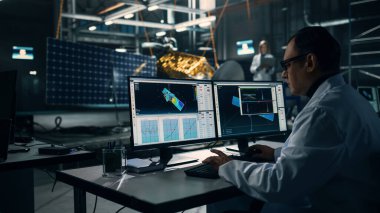 Erkek Mühendis Uydu İnşaatı 'nda çalışırken bilgisayar kullanıyor. Uzay Ajansı: Bilim adamı Uzay Keşfi Görevi için Uzay Aracı Programlama ve Toplama için Bilgisayar Yazılımı kullanıyor.