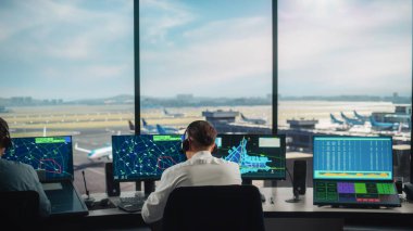 Modern bir havaalanı kulesinde çalışan çeşitli hava trafik kontrol ekibi. Ofis Odası Masaüstü Bilgisayarı ile dolu Navigasyon Ekranları, Uçak Ayrılışı ve Denetleyiciler için Gelen Veri.