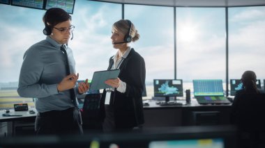 Havalimanı Kulesi 'nde Kulaklıklı Kadın ve Erkek Hava Trafik Kontrolörleri. Ofis Odası, Takım için Navigasyon Ekranları, Uçak Gidiş ve Gelen Veri ile Masaüstü Bilgisayarı ile Doludur.