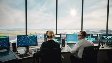 Modern bir havaalanı kulesinde çalışan çeşitli hava trafik kontrol ekibi. Ofis Odası Masaüstü Bilgisayarı ile dolu Navigasyon Ekranları, Uçak Ayrılışı ve Denetleyiciler için Gelen Veri.